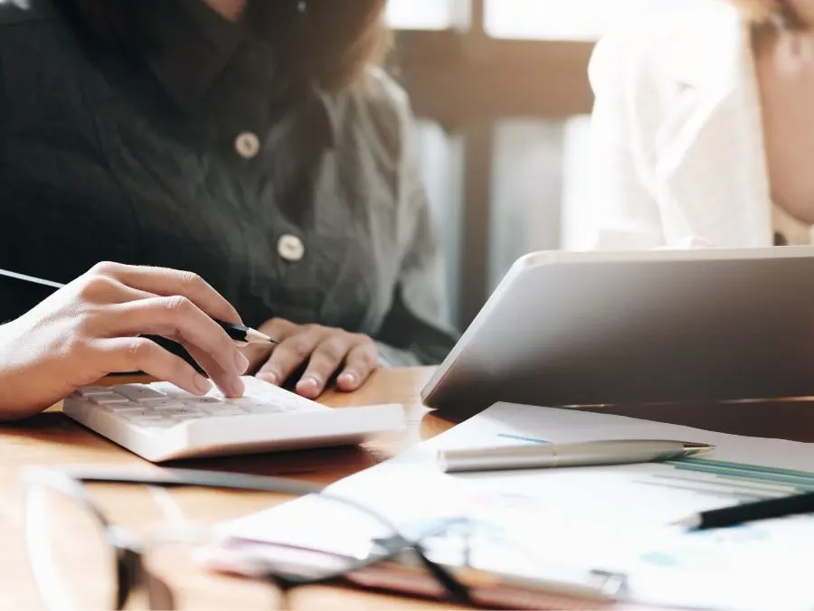 Une personne travaille sur la calculatrice et prend des notes.