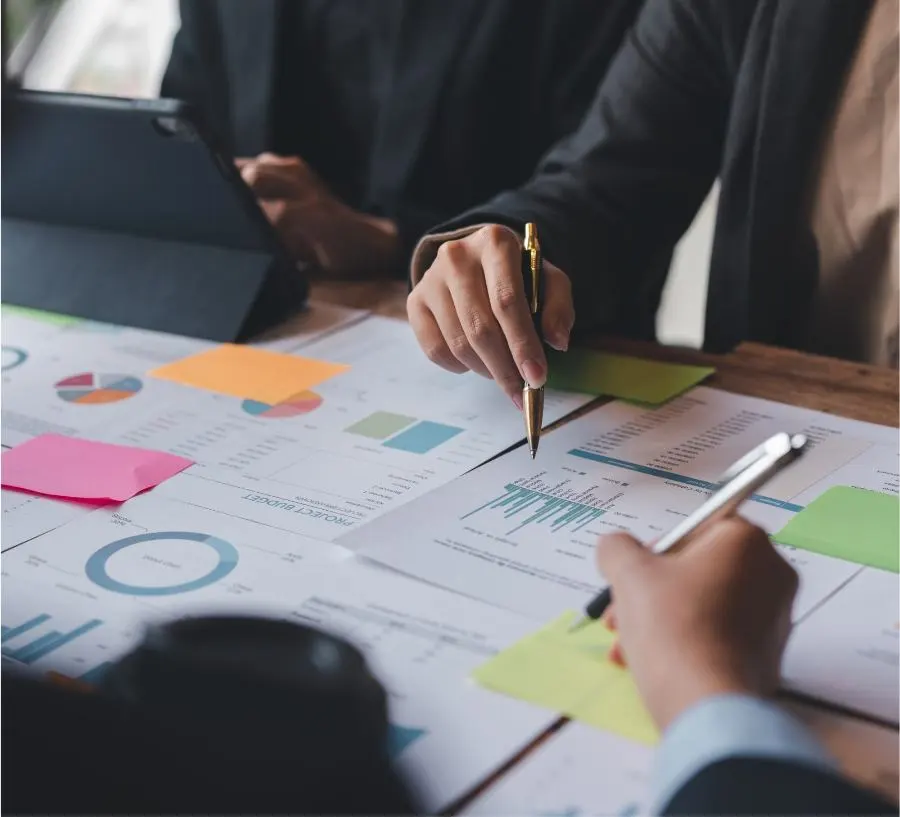 Trois personnes analysent différents graphiques posés devant elles sur la table.